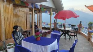 a woman sitting on a balcony with a table and an umbrella at Dafey Homestay in Darjeeling