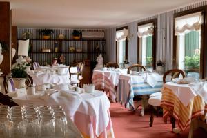 a dining room with tables with white tablecloths at Villa Abbazia Relais & Chateaux in Follina