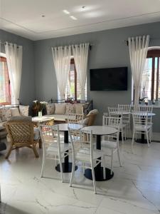 a living room with white chairs and tables and a tv at The White Troy in Sarandë