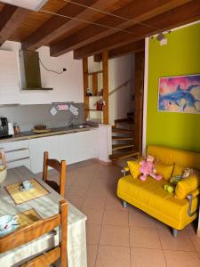 a living room with a yellow couch and a kitchen at Il Giardino di Bronto-lo in Crosare