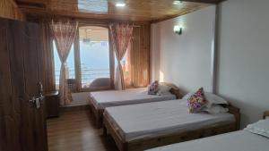 a room with two beds and a window at Dafey Homestay in Darjeeling