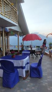 a table with blue chairs and a red umbrella at Dafey Homestay in Darjeeling