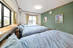 two beds in a room with green walls at リトリート禅の宿 in Owariasahi
