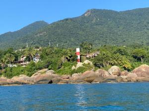 a lighthouse on a rocky island in the water at Chalé com vista na vila centro histórico in Ilhabela