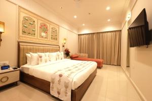 a hotel room with a large bed and a television at Dhiraj Dham in Nāthdwāra