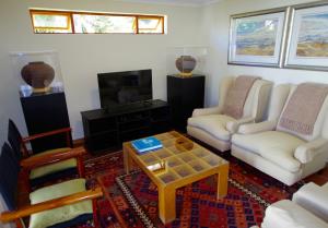 sala de estar con 2 sillas y mesa de centro en Graskop Harrie's Cottage, en Graskop