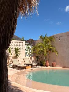 a swimming pool with two chairs and a palm tree at Le Bohémien Suites Cabana in Dalung