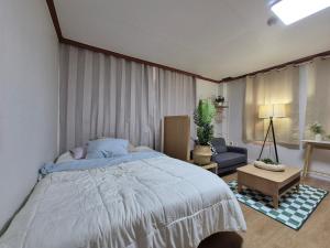 a bedroom with a bed and a couch and a chair at the stay Paju in Paju