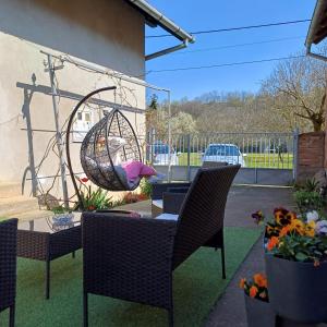 a patio with chairs and a swing and flowers at Sunstation in Šarengrad
