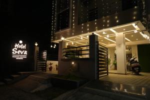 a lit up building with a sign and a motorcycle at Hotel Seva in Nagpur