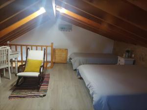 a attic bedroom with two beds and a chair at Casa Emília & Alda in Juncal
