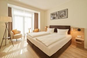 a bedroom with a large bed and a chair at Hotel und Weingut Karlsmühle in Mertesdorf +49 photos