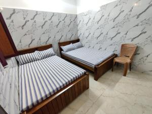 two twin beds in a room with a chair at Siva Lodge in Rāmeswaram