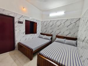 two beds in a room with white walls at Siva Lodge in Rāmeswaram