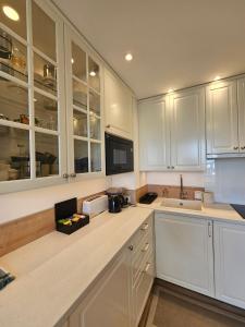 a kitchen with white cabinets and a sink at Méva in Courseulles-sur-Mer +8 photos