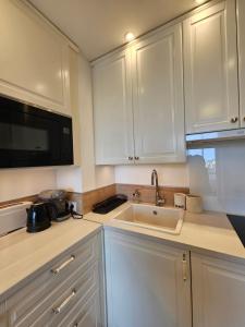 a kitchen with white cabinets and a sink and a microwave at Méva in Courseulles-sur-Mer