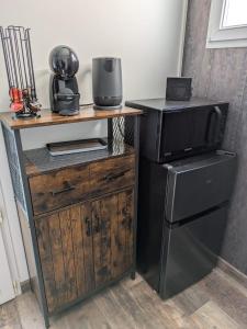 a microwave on a wooden stand next to a refrigerator at Chambre la Belle Étape in Martinet