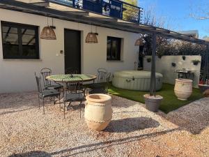 a patio with a table and chairs and a tub at Le Ciné Lodge Provence in Flassans-sur-Issole