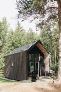 a small cabin with a black roof at Liedaga namiņš in Mērsrags