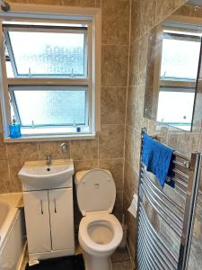 a bathroom with a toilet and a sink and a window at Massive cozy room with shared bathroom in Thornton Heath