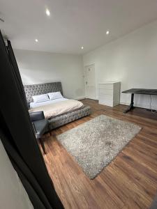 a bedroom with a bed and a table and a rug at Massive cozy room with shared bathroom in Thornton Heath