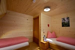 two beds in a wooden room with red pillows at Ferienhaus Oberboden in Schröcken