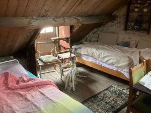 a attic room with two beds and a chair at Het werkhuis, terug in de tijd in Uden
