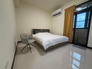 a bedroom with a bed and a chair and a window at Siwei B&B in Hou-k'u-t'an