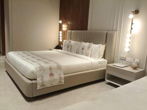 a bedroom with a large white bed with white pillows at Dhiraj Dham in Nāthdwāra