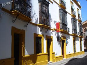 ein gelbes und weißes Gebäude mit Balkonen auf einer Straße in der Unterkunft Bed & Breakfast Naranjo in Sevilla