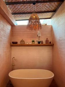 a bath tub in a bathroom with a chandelier at Le Bohémien Suites Cabana in Dalung +20 photos