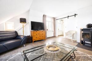 a living room with a couch and a tv at Vierseitenhof Hasenfelde - Ferienwohnung Feldblick in Steinhöfel