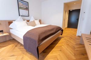 ein großes Bett in einem Zimmer mit Holzboden in der Unterkunft Das Exter - modernes Self Check-in Hotel am Chiemsee in Übersee