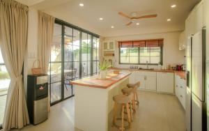 a kitchen with white cabinets and a island with bar stools at Fishman Beachfront Villas in Haad Pleayleam