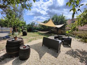a patio with two barrels and chairs and a hammock at Apartamenty Tarcal in Tarcal