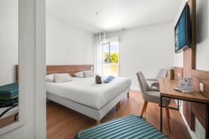 a bedroom with a bed and a desk and a tv at Logis Hôtel La Forestière in Biscarrosse-Plage +34 photos