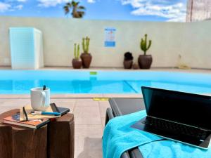 a laptop sitting on a table next to a swimming pool at Ocean Suite by SHC with heated pool only for adults in Telde