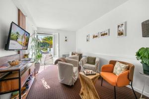 a living room with orange chairs and a tv at Logis Hôtel La Forestière in Biscarrosse-Plage