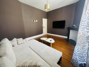 a bedroom with a white bed and a tv at Logement Océan in Boulogne-sur-Mer +2 photos