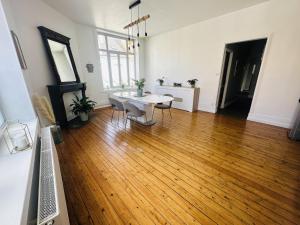 a living room with a table and chairs on a wooden floor at Logement Océan in Boulogne-sur-Mer
