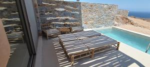 a balcony with three benches and a swimming pool at Piperi Suites in Kithnos