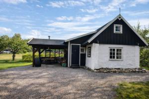 a small white cottage with a black roof at Grynnan in Skå