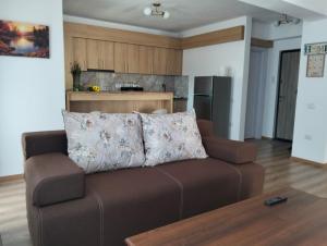 a living room with a brown couch and a kitchen at GH Apartments 2 in Gura Humorului
