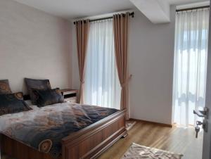 a bedroom with a large bed and large windows at GH Apartments 2 in Gura Humorului