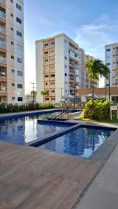 a large swimming pool in a city with buildings at Aruana Azul 502 - Apto com AR, PISCINA, Varanda Integrada - Aluguel por Temporada in Aracaju