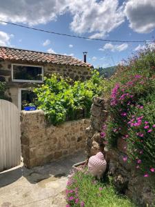 a stone house with flowers in the yard at Le Mafaté - Vallée de l'Eyrieux in Saint Maurice en Chalencon