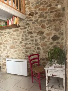 a red chair sitting next to a stone wall at Le Mafaté - Vallée de l'Eyrieux in Saint Maurice en Chalencon