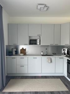 a white kitchen with white cabinets and a microwave at Sõbra SPA Villa Haapsalu lähistel kaunis looduses in Nõmme +19 photos