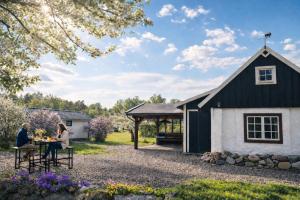 a couple sitting at a table in front of a black and white building at Grynnan in Skå +17 photos