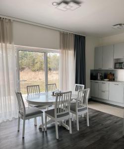 a kitchen and dining room with a white table and chairs at Sõbra SPA Villa Haapsalu lähistel kaunis looduses in Nõmme